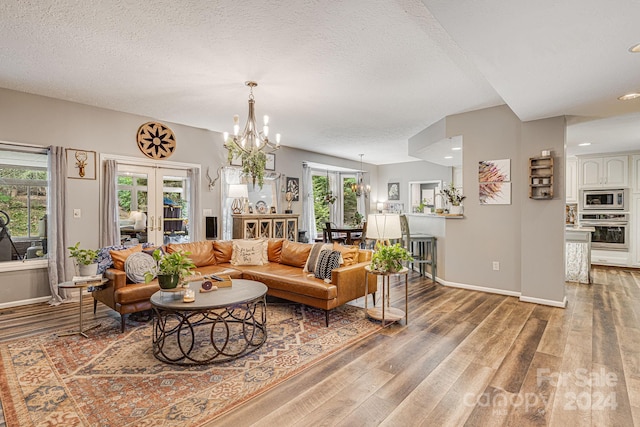 living room featuring a textured ceiling, an inviting chandelier, plenty of natural light, and french doors