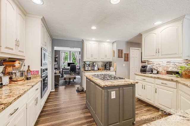 kitchen with light stone countertops, appliances with stainless steel finishes, a center island, dark hardwood / wood-style flooring, and decorative backsplash