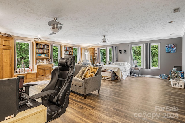 bedroom with ceiling fan, wood-type flooring, crown molding, and a textured ceiling