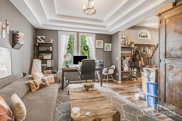 office featuring wood-type flooring, an inviting chandelier, and a tray ceiling