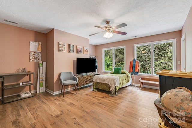 bedroom featuring ceiling fan, a textured ceiling, and light wood-type flooring