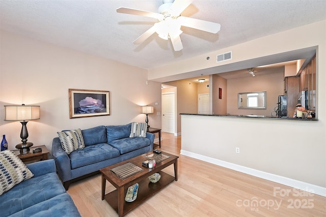 living room featuring ceiling fan, a textured ceiling, and light hardwood / wood-style flooring