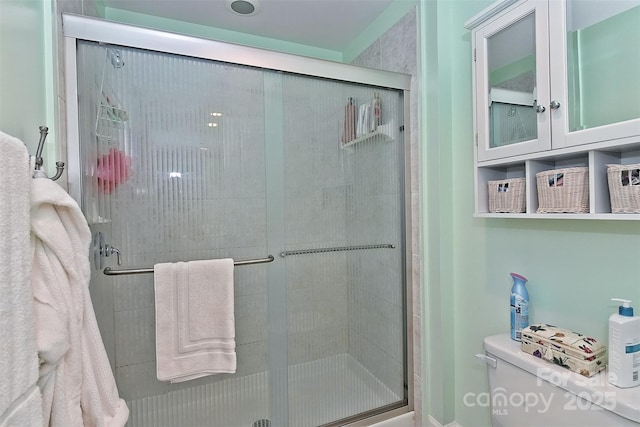 bathroom with a shower with door and toilet