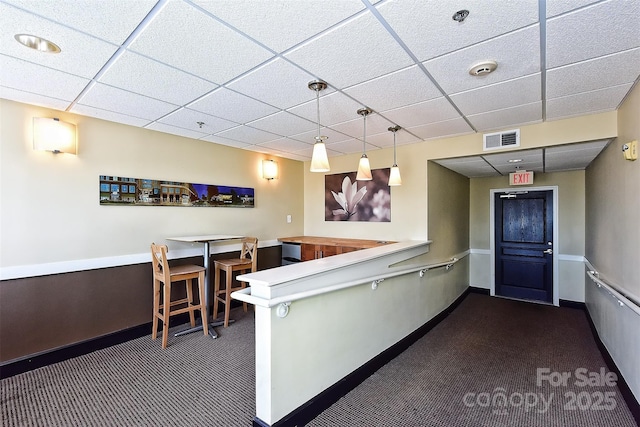 kitchen featuring a drop ceiling, dark carpet, and kitchen peninsula