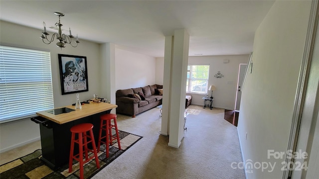 dining room featuring light carpet, baseboards, and a notable chandelier