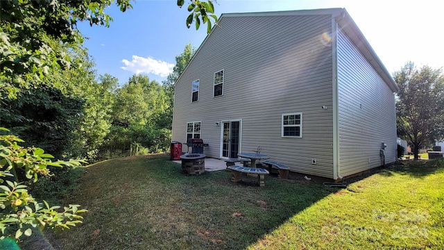 rear view of house with a lawn and a fire pit