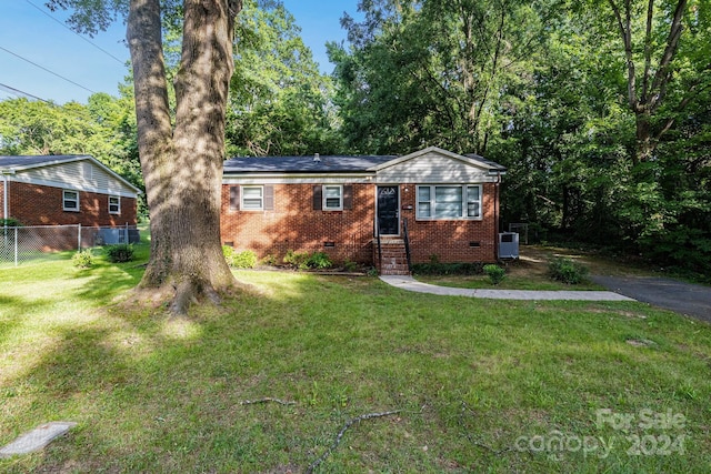 ranch-style home featuring central AC unit and a front lawn