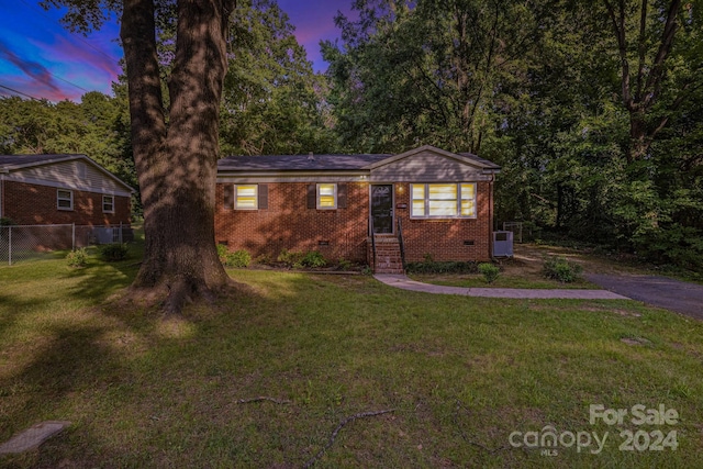 ranch-style house featuring central AC unit and a lawn