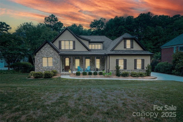 view of front of home with a front yard, stone siding, and stucco siding