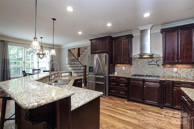 kitchen featuring sink, stainless steel appliances, wall chimney exhaust hood, and a spacious island