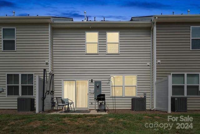 rear view of house featuring central AC unit, a yard, and a patio