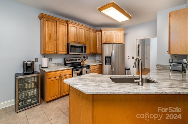 kitchen featuring wine cooler, stainless steel appliances, kitchen peninsula, sink, and light stone countertops