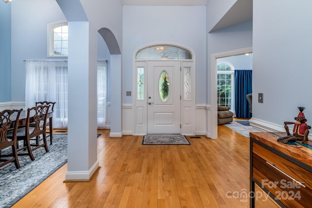 entrance foyer with a wealth of natural light, light hardwood / wood-style floors, and a towering ceiling