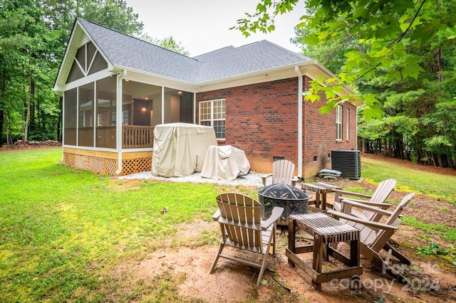 rear view of house featuring a yard, cooling unit, a sunroom, and an outdoor fire pit