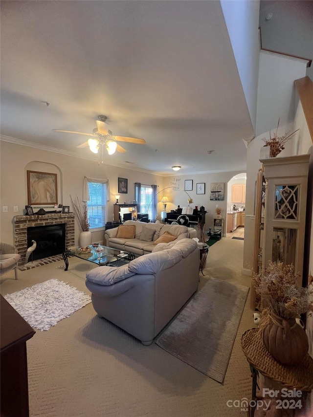 carpeted living room featuring a fireplace, ornamental molding, and ceiling fan