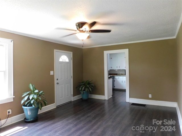 foyer entrance featuring ceiling fan, a textured ceiling, dark hardwood / wood-style flooring, and ornamental molding