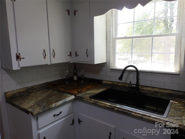 kitchen featuring white cabinets, backsplash, and sink