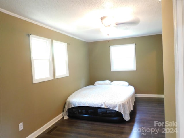 bedroom featuring dark wood-type flooring, ceiling fan, ornamental molding, and a textured ceiling