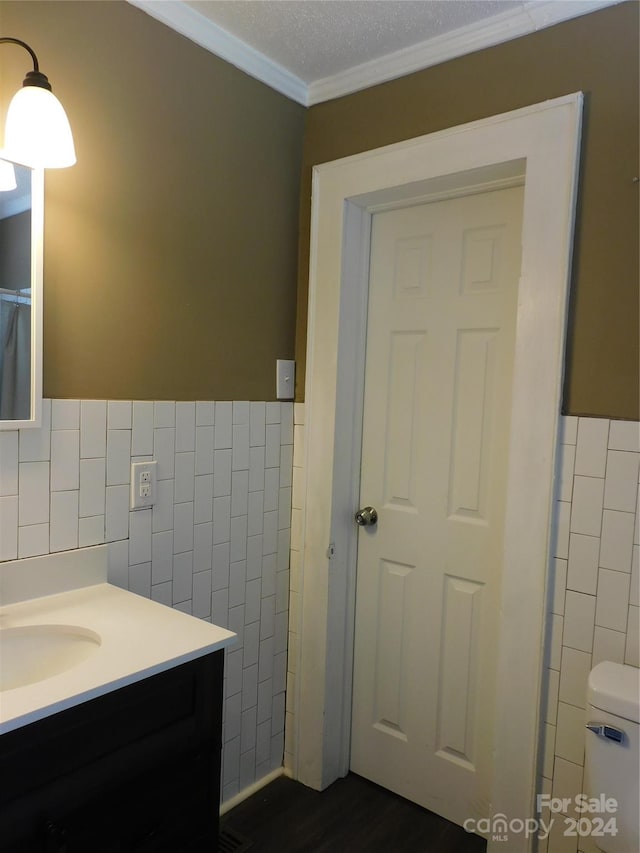 bathroom with toilet, vanity, tile walls, and crown molding