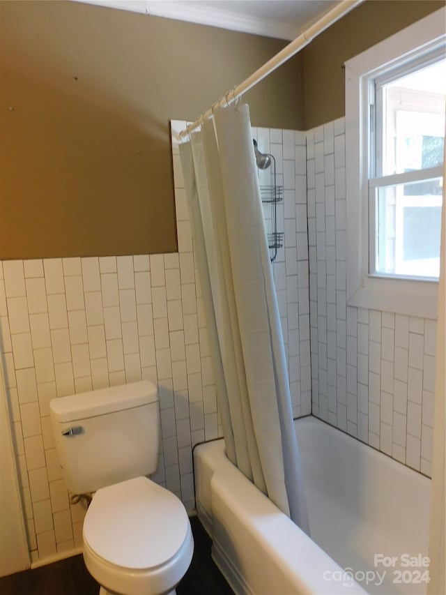 bathroom with tile walls, toilet, and shower / tub combo