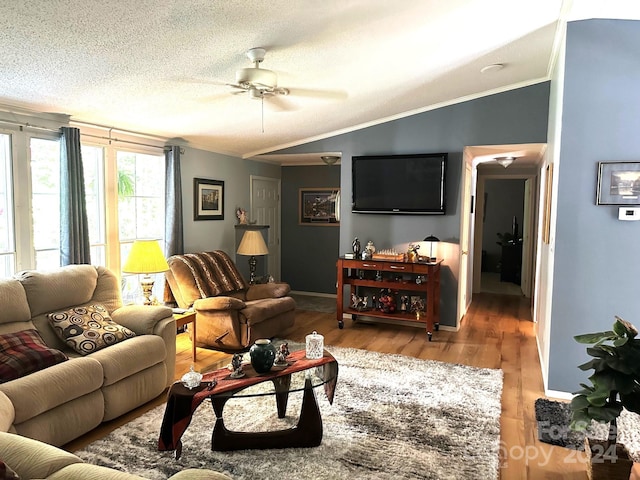 living room featuring ceiling fan, vaulted ceiling, hardwood / wood-style flooring, a textured ceiling, and ornamental molding