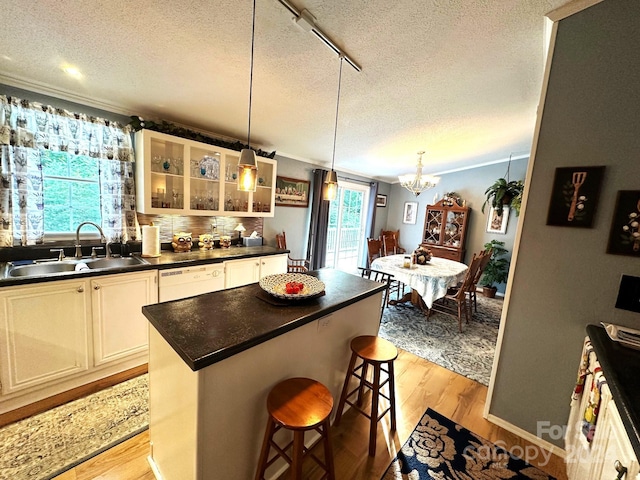 kitchen featuring light hardwood / wood-style floors, a center island, a kitchen bar, sink, and white cabinets