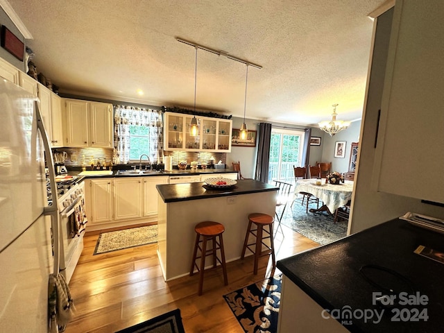 kitchen with white appliances, a center island, track lighting, white cabinetry, and a kitchen breakfast bar