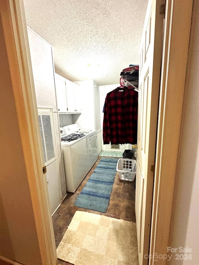 laundry area with cabinets, a textured ceiling, and washing machine and dryer