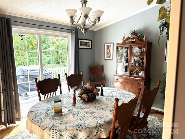 dining area with an inviting chandelier, crown molding, a textured ceiling, and hardwood / wood-style floors