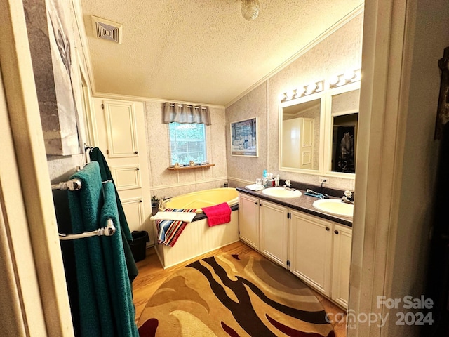 bathroom with a textured ceiling, wood-type flooring, vaulted ceiling, ornamental molding, and a washtub