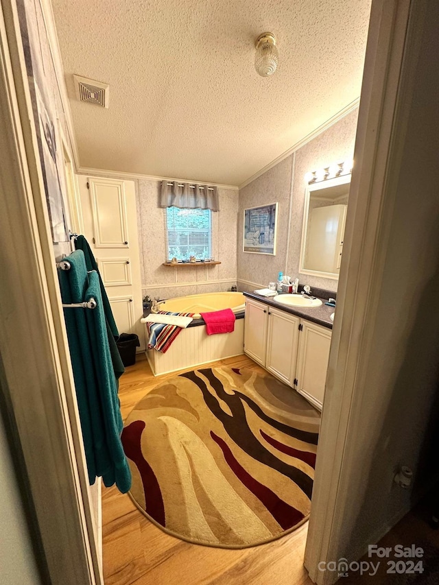 bathroom with hardwood / wood-style flooring, a washtub, a textured ceiling, and vanity