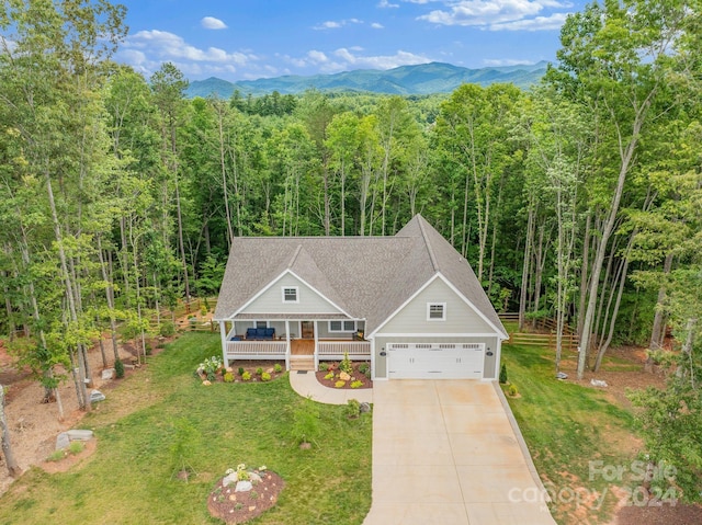 view of front of house featuring a mountain view, a garage, covered porch, and a front lawn