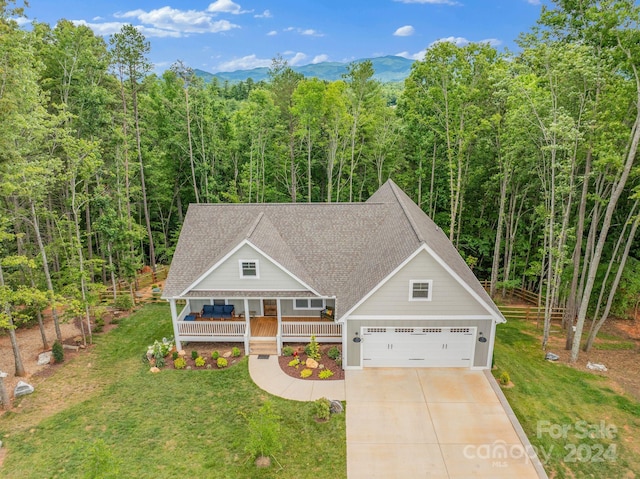 view of front facade featuring a mountain view, a front lawn, covered porch, and a garage