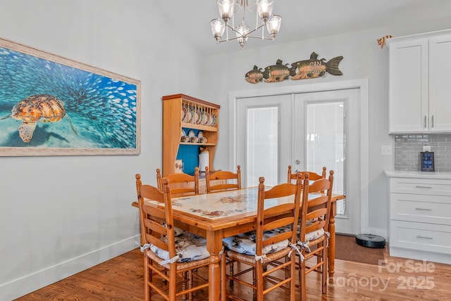 dining space with baseboards, light wood finished floors, an inviting chandelier, and lofted ceiling