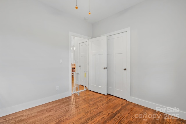 unfurnished bedroom with a closet, baseboards, and wood finished floors
