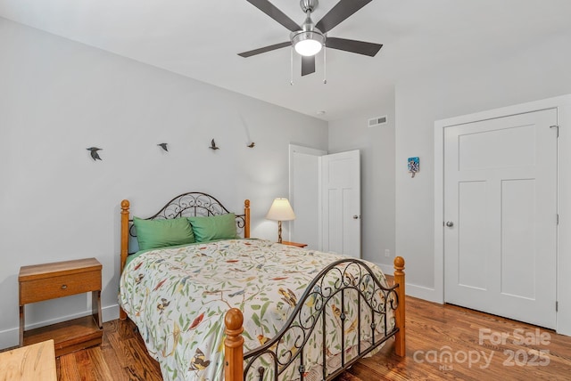 bedroom featuring visible vents, baseboards, ceiling fan, and wood finished floors