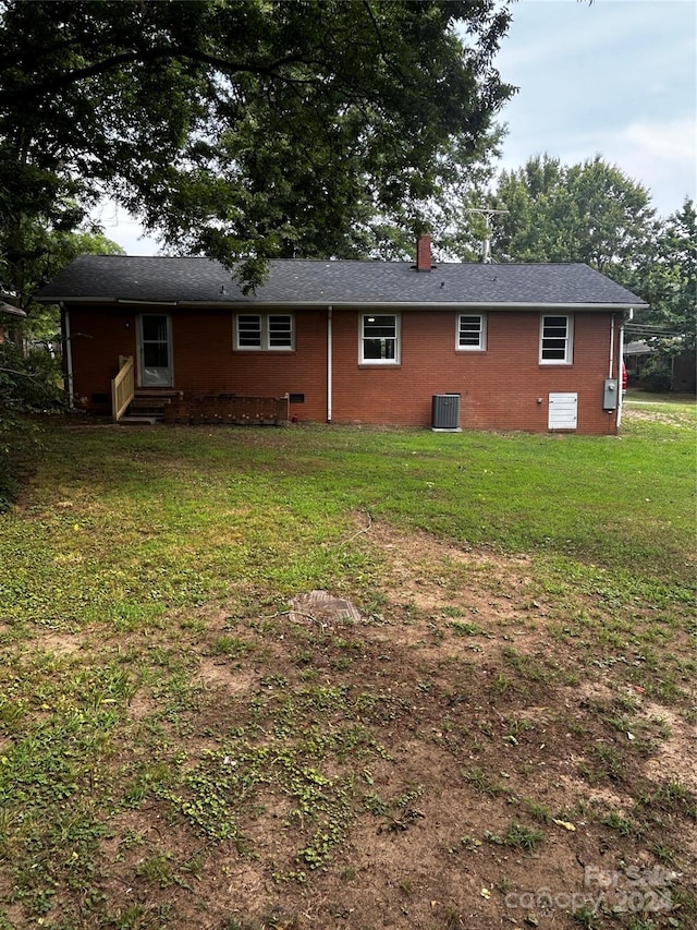 rear view of property with a lawn and central air condition unit