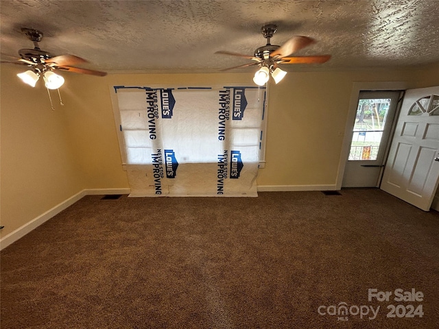 empty room featuring a textured ceiling, ceiling fan, and carpet flooring