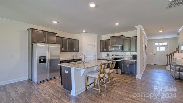 kitchen with tasteful backsplash, a kitchen island with sink, dark hardwood / wood-style floors, appliances with stainless steel finishes, and sink