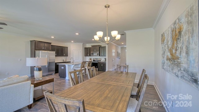 dining space with an inviting chandelier, sink, dark wood-type flooring, and crown molding