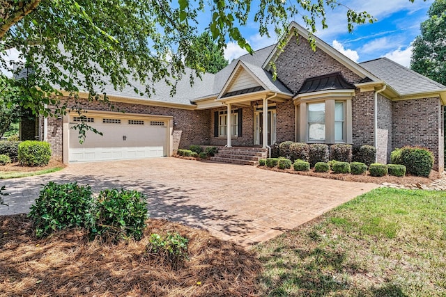 craftsman inspired home with a garage, brick siding, driveway, and roof with shingles