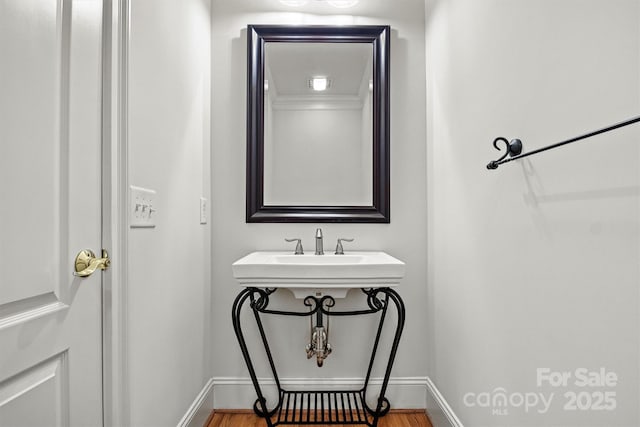 bathroom with a sink, baseboards, and wood finished floors