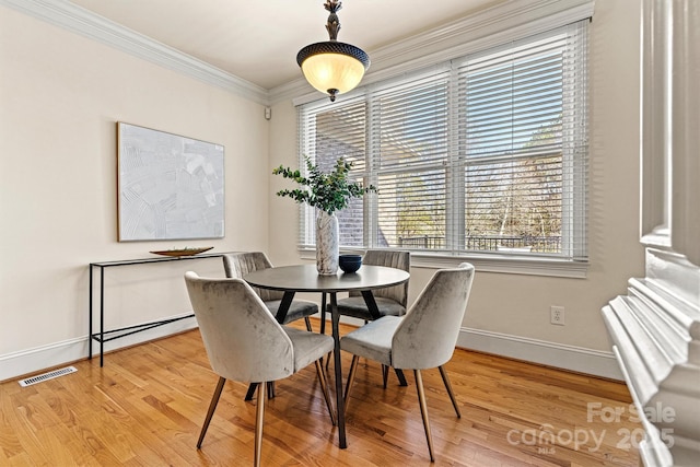 dining room featuring ornamental molding, wood finished floors, visible vents, and baseboards