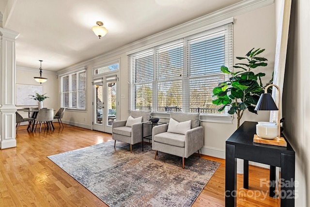 living area with light wood finished floors, decorative columns, and crown molding