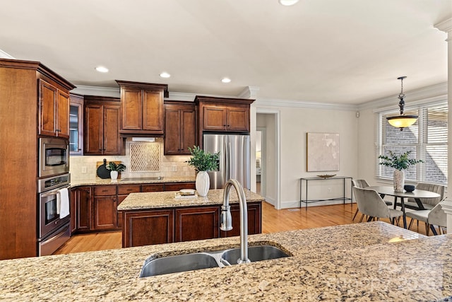 kitchen featuring glass insert cabinets, appliances with stainless steel finishes, hanging light fixtures, light stone countertops, and a sink