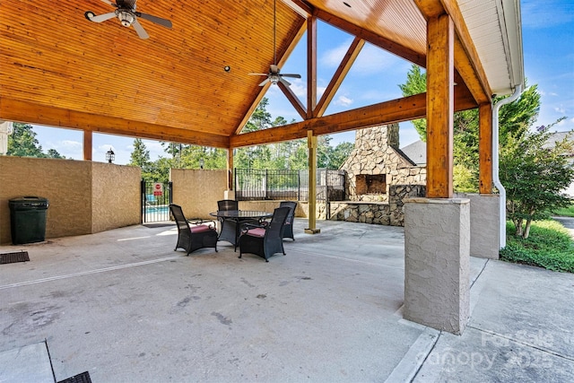 view of patio / terrace featuring ceiling fan, fence, an outdoor stone fireplace, and outdoor dining space