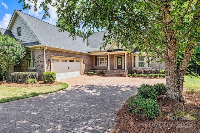 view of front of house featuring driveway, a shingled roof, a garage, and brick siding