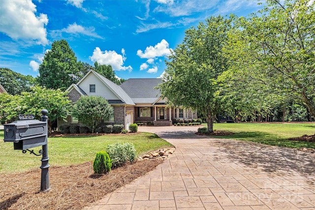 view of front facade featuring a front yard, decorative driveway, and brick siding