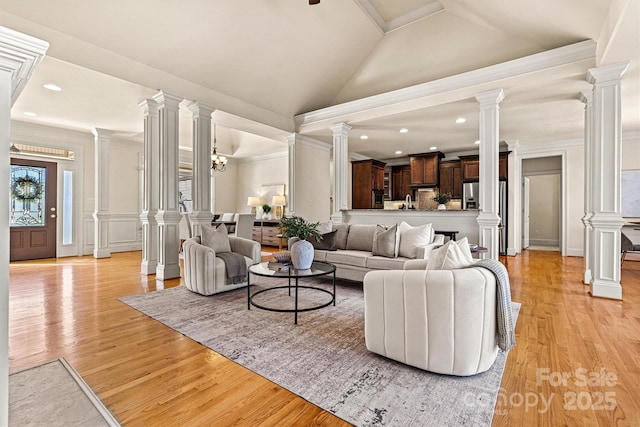 living area featuring ornate columns, light wood-style flooring, a decorative wall, and crown molding