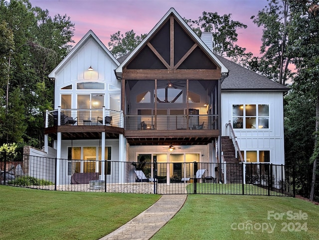 view of front facade featuring board and batten siding, a fenced backyard, a front lawn, and a ceiling fan